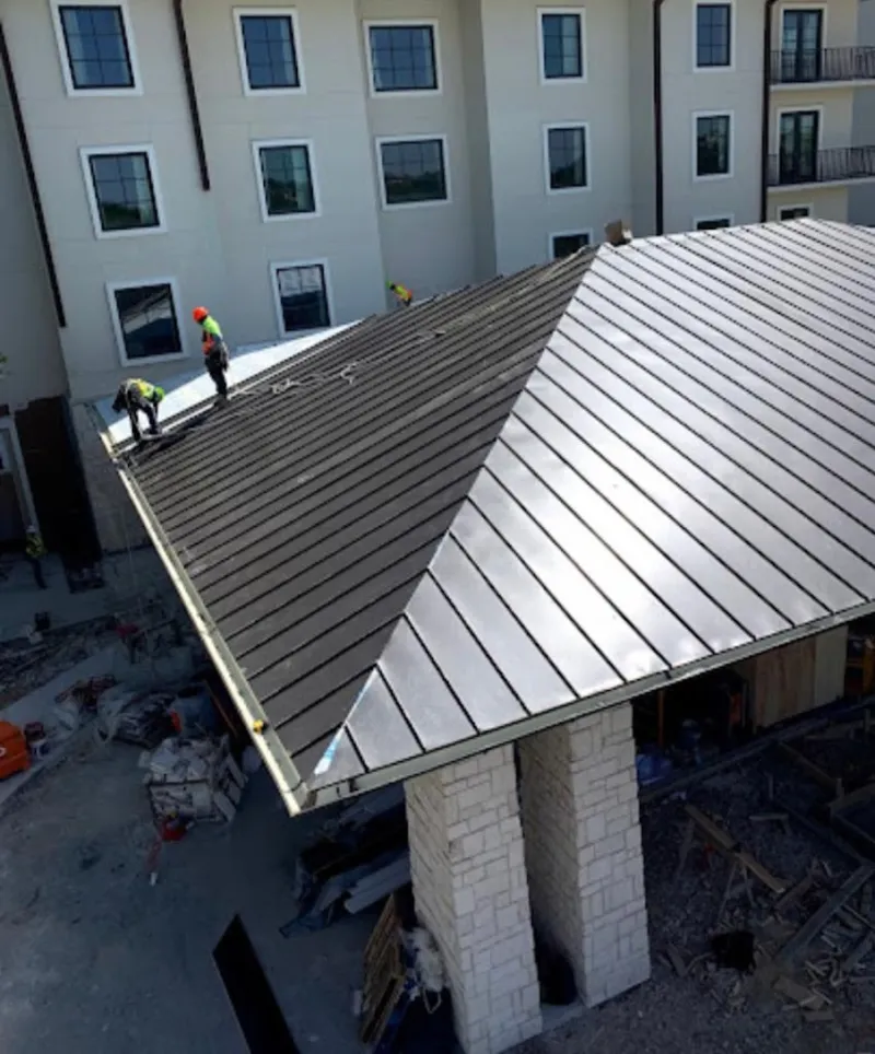 Crew installing standing seam metal roof panels on a commercial project in Grand Forks